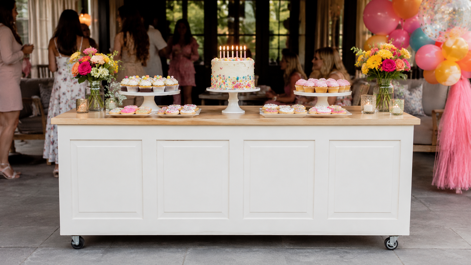 A straight white celebration cart styled with cake, cookies, balloons and birthday color.